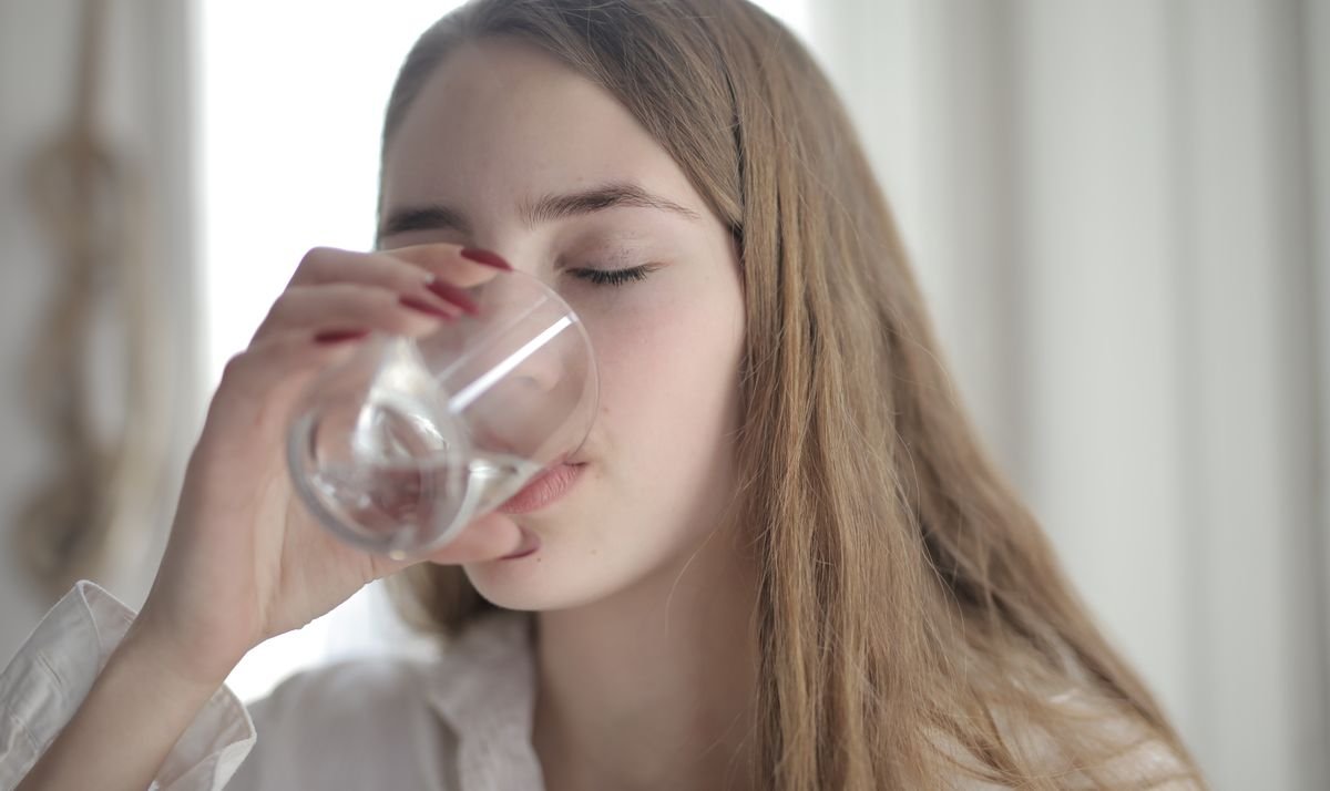 Person pausing mindfully with a glass of water at a calm retreat setting