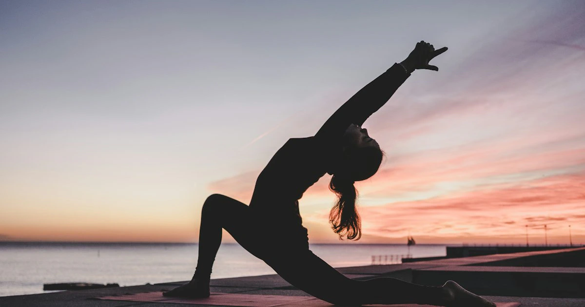A woman practising yoga outdoors at a wellness retreat, representing the holistic daily program of a Buchinger-style fast.