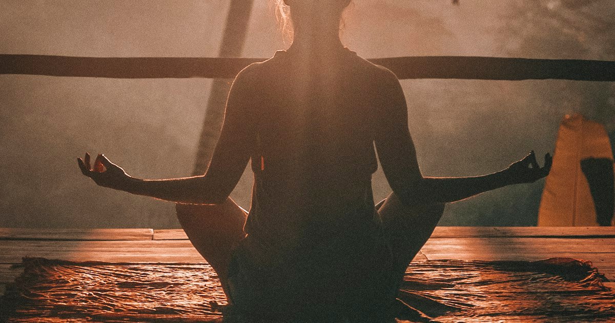 Person meditating at sunrise with a peaceful ocean view