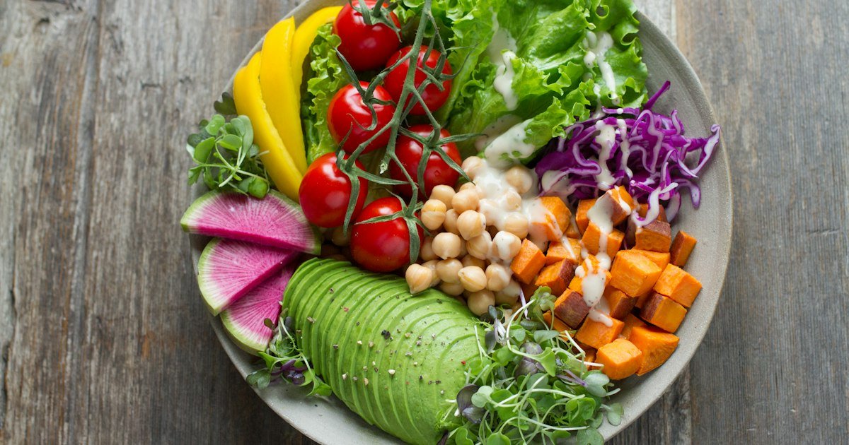 A vibrant vegetable salad bowl with fresh greens, tomatoes, and colorful produce representing gentle refeeding foods